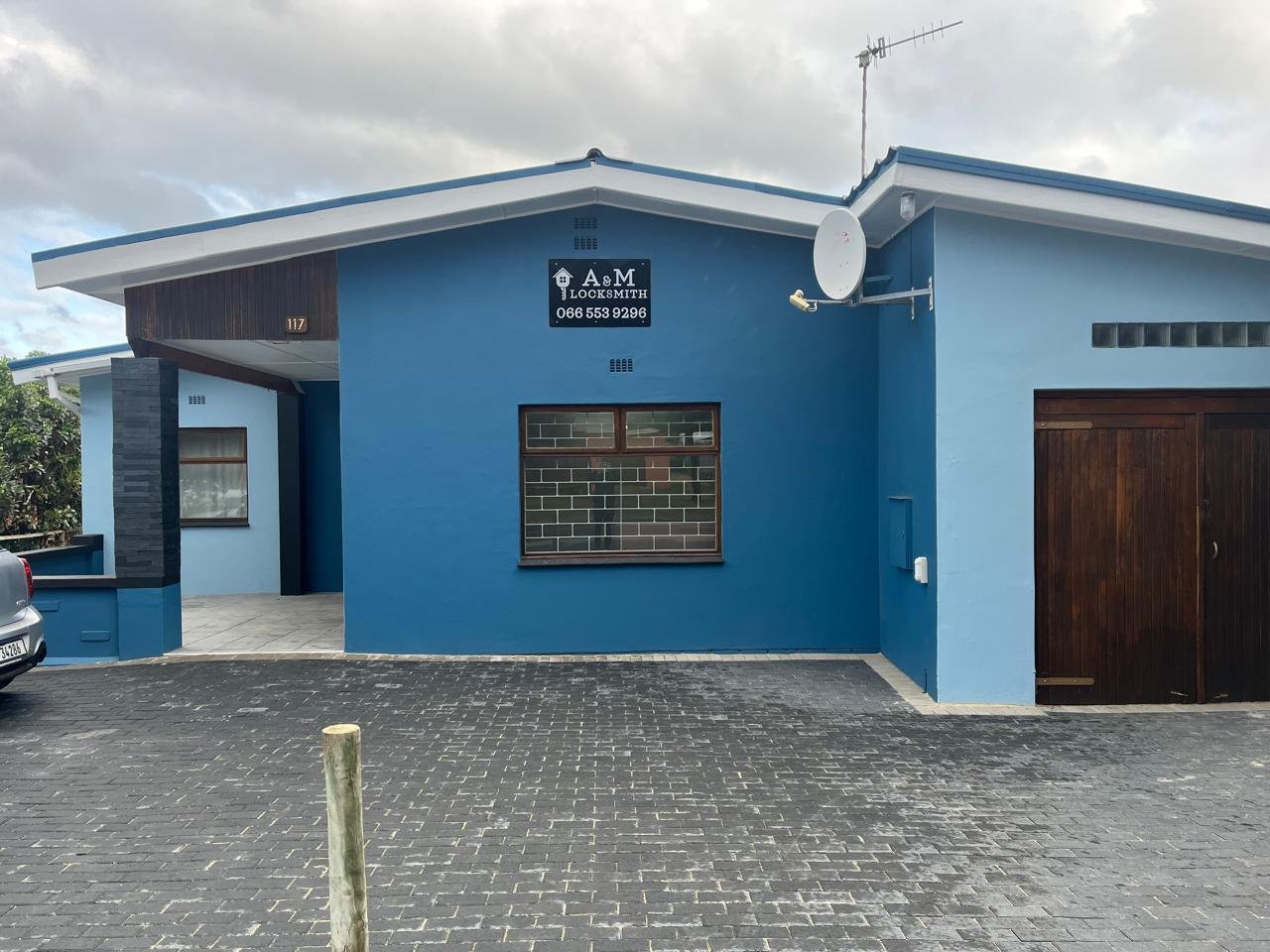 The A & M Locksmith building at 117 Main Road, Kleinmond: a blue single-storey shop with the black sign above the window and a paved parking bay in front